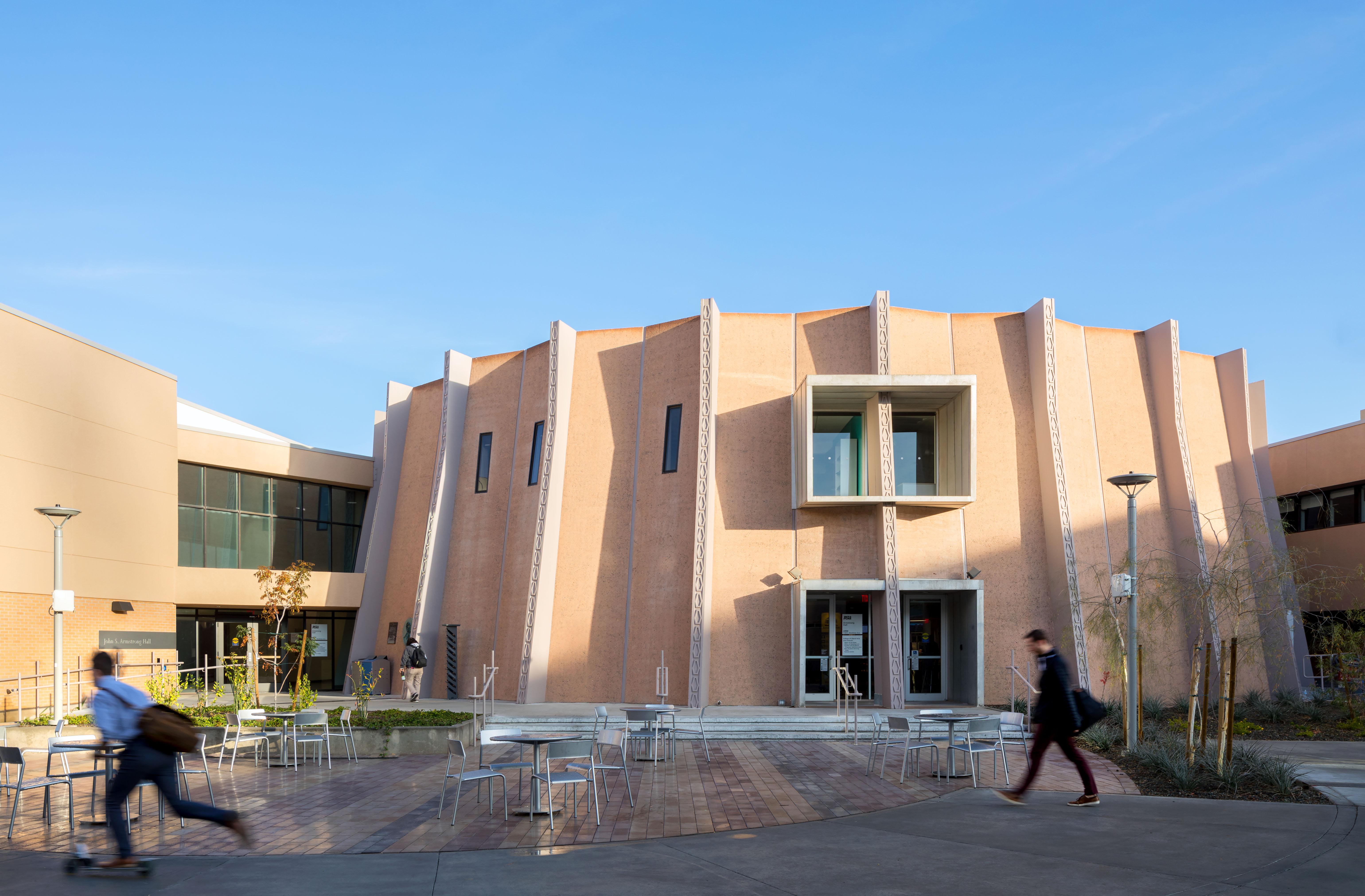 Two students walking in front of Armstrong Hall with shadows on the building